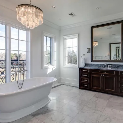 Spacious bathroom with a freestanding bathtub, custom double sink vanity, and marble floor