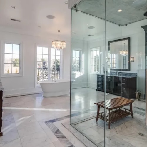 Modern bathroom with glass-enclosed shower, freestanding tub, and custom dark wood vanity