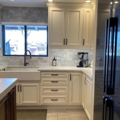 Modern kitchen with cream-colored custom cabinets, farmhouse sink, and stainless steel appliances